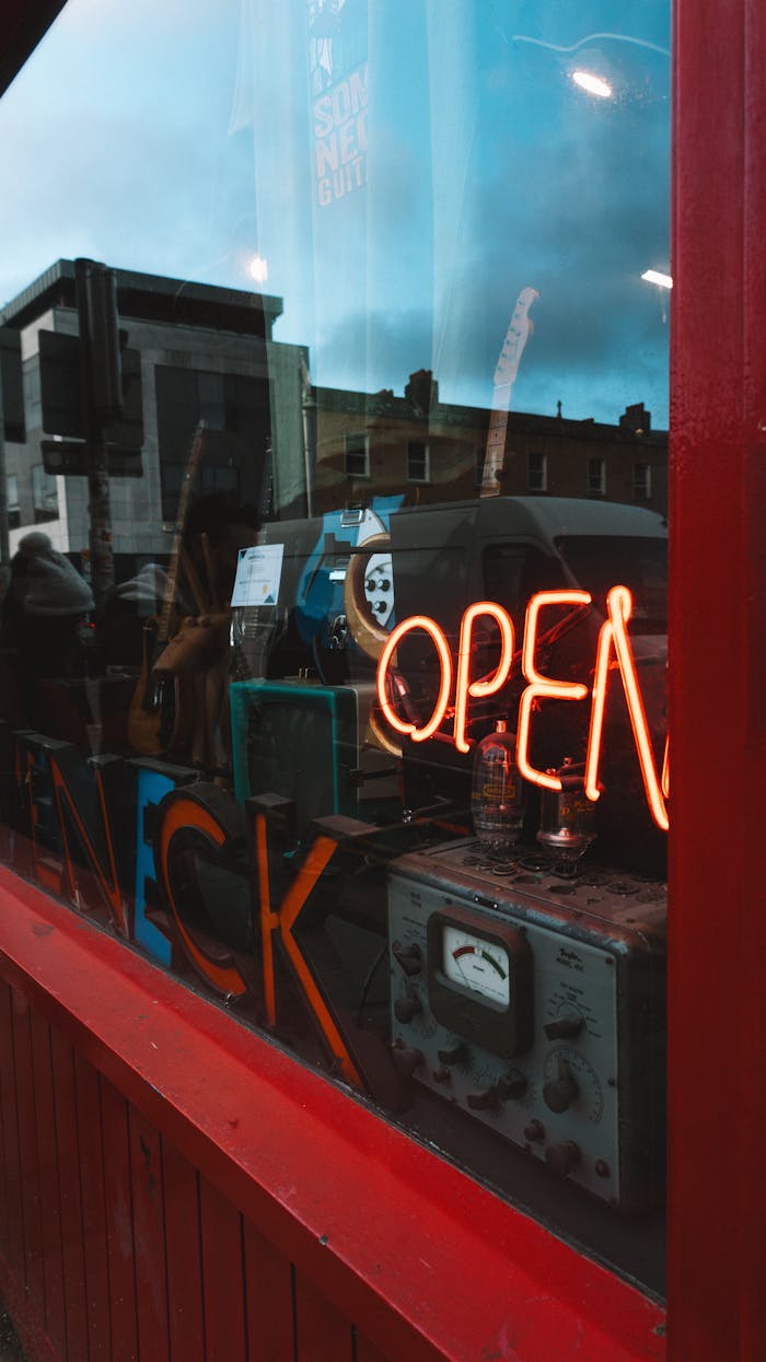 A neon sign in a window that says open